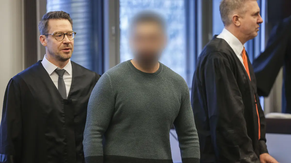 Der Angeklagte (M) mit seinen Anwältenbeim Prozessauftakt. 