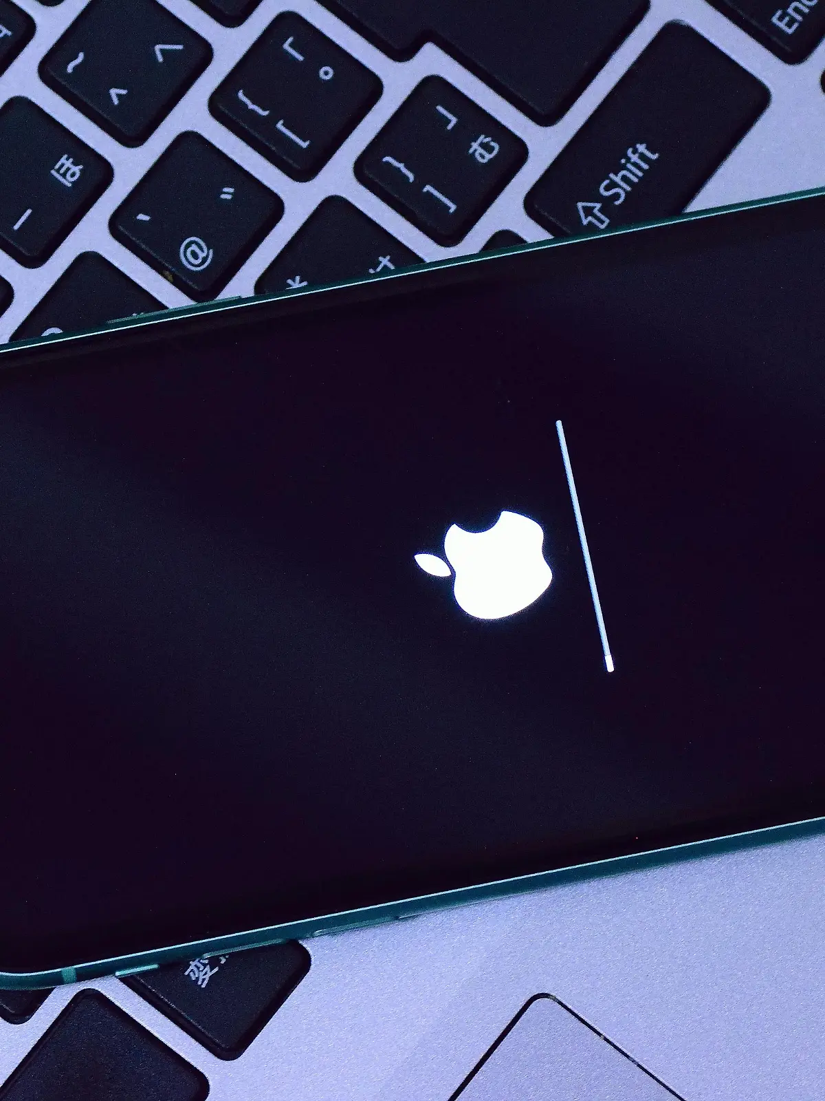 Ein iPhone während eines iOS-Updates liegt auf einer Computer-Tastatur.