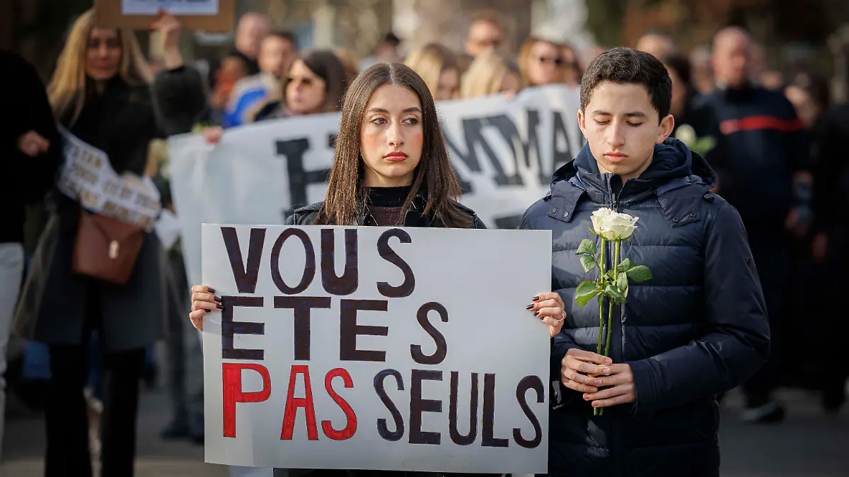 „Vous etes pas seuls” (Ihr seid nicht allein) steht auf ddem Plakat, mit dem dieses Parr den Schweigemarsch von etwa 1.000 Teilnehmern in Lutry anführen.