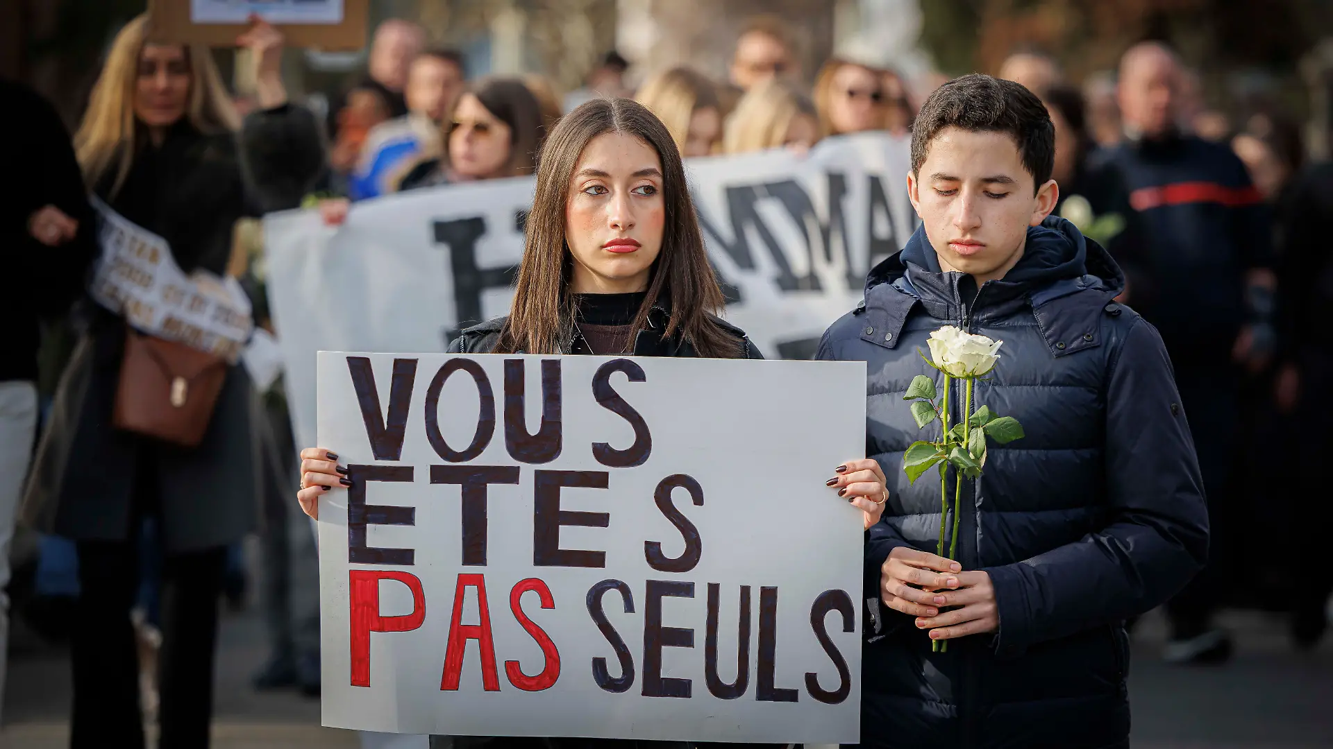 „Vous etes pas seuls” (Ihr seid nicht allein) steht auf ddem Plakat, mit dem dieses Parr den Schweigemarsch von etwa 1.000 Teilnehmern in Lutry anführen.
