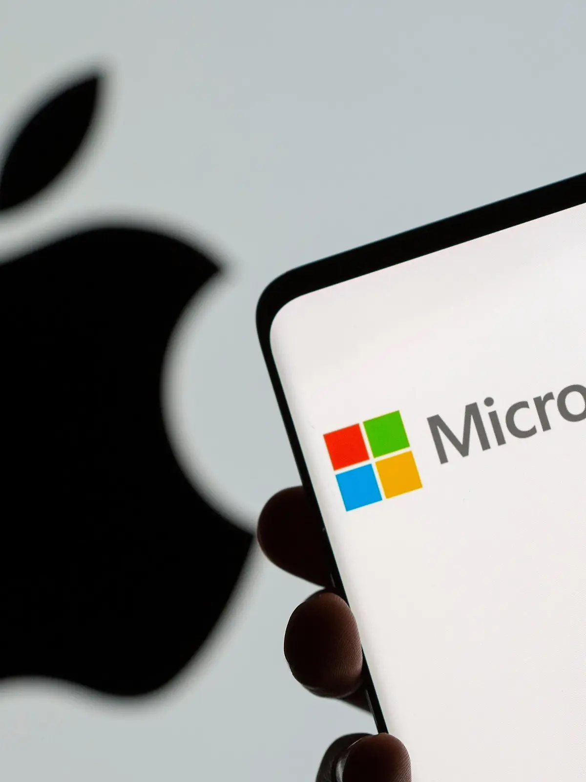 Microsoft logo is seen on the smartphone in front of displayed Apple logo in this illustration taken, July 26, 2021. REUTERS/Dado Ruvic/Illustration