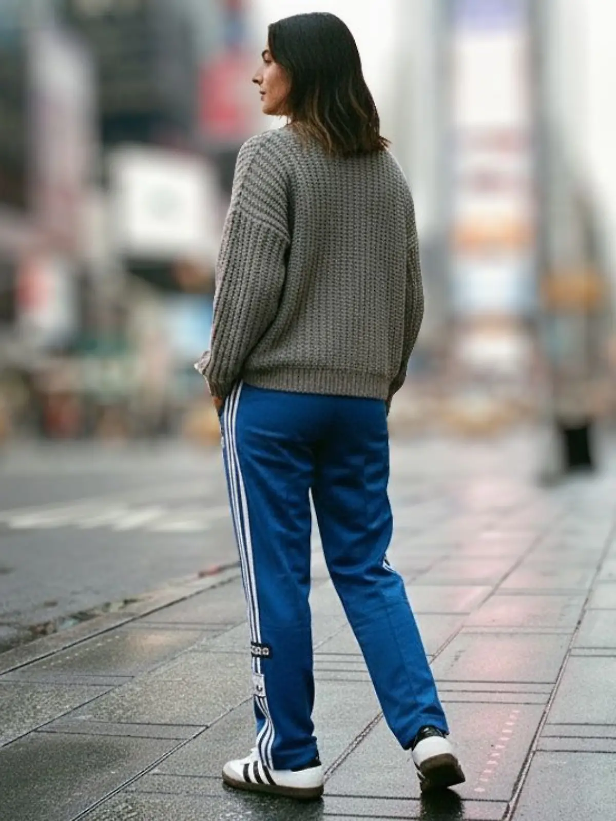 Frau in blauer Trainingshose und Strickpullover auf der Straße.
