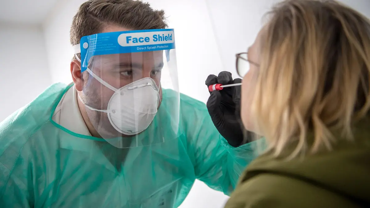 ARCHIV - 29.12.2020, Niedersachsen, Nordhorn: Ein Abstrich für einen PCR-Test wird von einem Mitarbeiter im Corona-Testzentrum genommen. Die deutschen Gesundheitsämter haben dem Robert Koch-Institut (RKI) 32.552 Corona-Neuinfektionen binnen 24 Stunden gemeldet. Außerdem wurden 964 neue Todesfälle verzeichnet, wie das RKI am Donnerstagmorgen bekanntgab. Foto: Sina Schuldt/dpa +++ dpa-Bildfunk +++