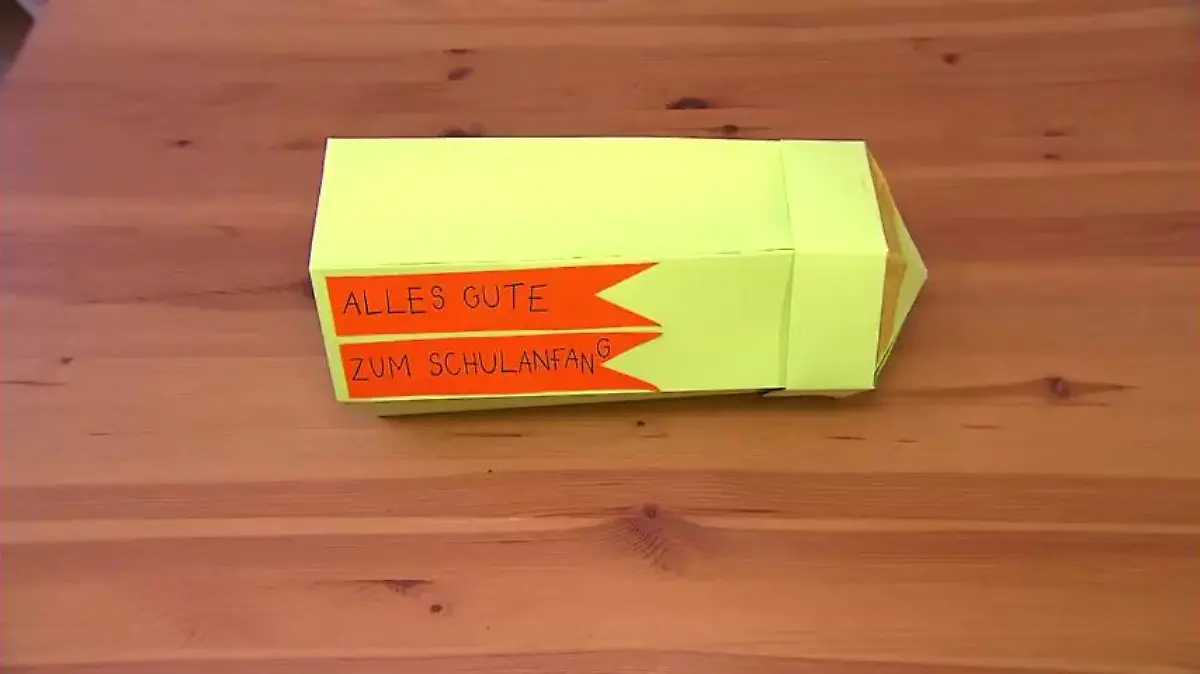 Schultüte in Stiftform liegt auf einem Holzboden