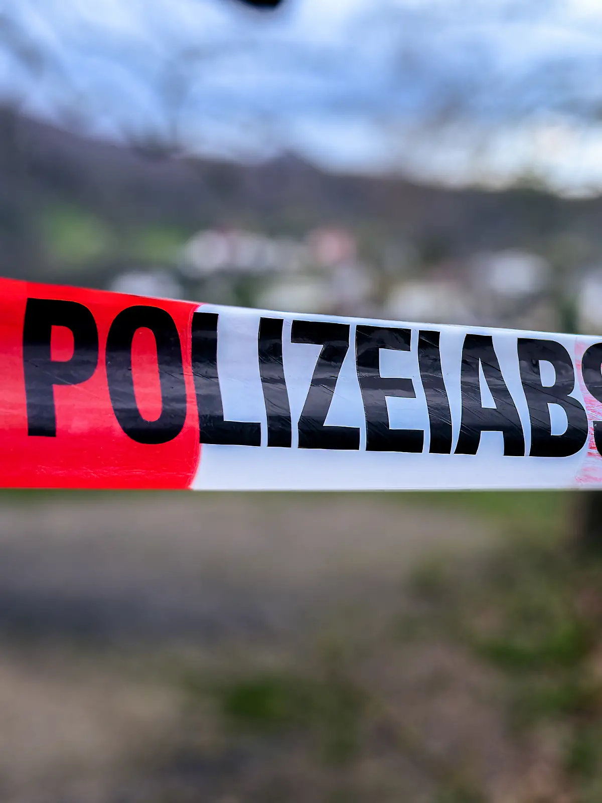 German  crime  scene  or  police  barrier  tape  in  a  park  saying  'Polizeiabsperrung',  meaning