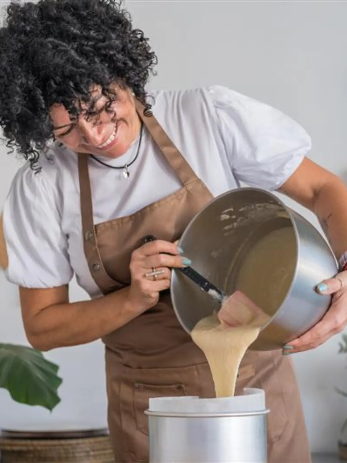 Frau gießt Rührteig in eine Backform.