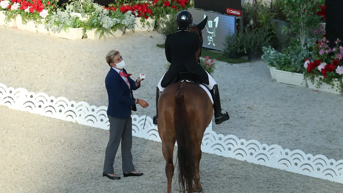 25.07.2021, Japan, Tokio: Pferdesport/Dressur: Olympia, Vorkampf, Einzel, Grand Prix, Baji Koen Equestrian Park. Caroline Chew aus Singapur auf Pferd Tribiani muss die Prüfung unterbrechen. Eine Richterin steht neben ihr und hält ein Taschentuch mit Blut in der Hand, welches aus dem Maul des Pferdes stammt. Foto: Friso Gentsch/dpa +++ dpa-Bildfunk +++
