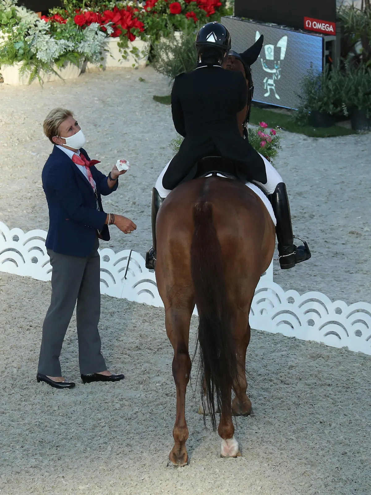 25.07.2021, Japan, Tokio: Pferdesport/Dressur: Olympia, Vorkampf, Einzel, Grand Prix, Baji Koen Equestrian Park. Caroline Chew aus Singapur auf Pferd Tribiani muss die Prüfung unterbrechen. Eine Richterin steht neben ihr und hält ein Taschentuch mit Blut in der Hand, welches aus dem Maul des Pferdes stammt. Foto: Friso Gentsch/dpa +++ dpa-Bildfunk +++
