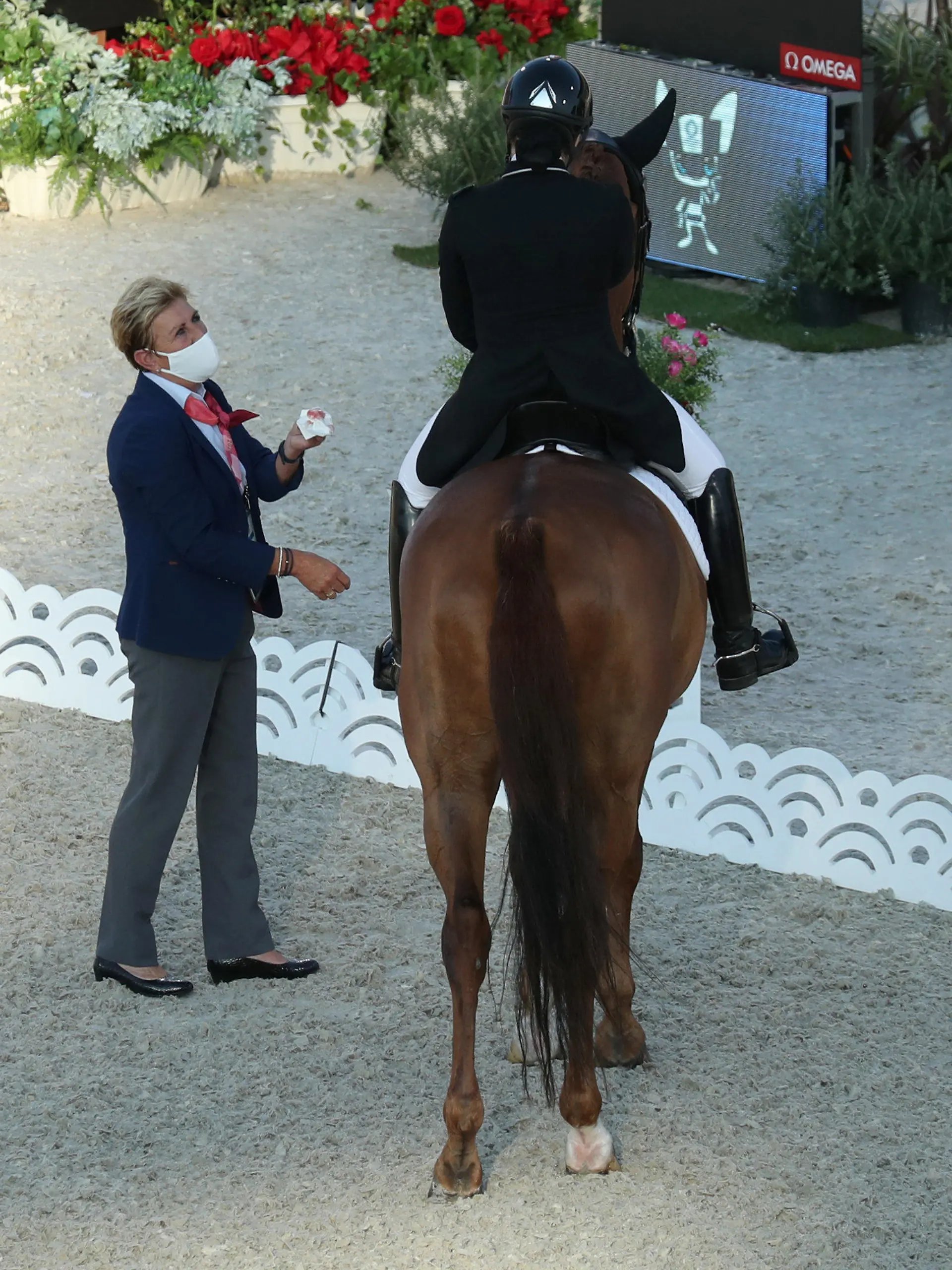 25.07.2021, Japan, Tokio: Pferdesport/Dressur: Olympia, Vorkampf, Einzel, Grand Prix, Baji Koen Equestrian Park. Caroline Chew aus Singapur auf Pferd Tribiani muss die Prüfung unterbrechen. Eine Richterin steht neben ihr und hält ein Taschentuch mit Blut in der Hand, welches aus dem Maul des Pferdes stammt. Foto: Friso Gentsch/dpa +++ dpa-Bildfunk +++