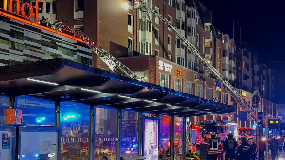 14.02.2026, Schleswig-Holstein, Kiel: Einsatzkräfte der Feuerwehr arbeiten auf Drehleitern an einem Wohnhaus über dem Einkaufszentrum Sophienhof in der Kieler Innenstadt in dem am Abend ein Brand ausgebrochen war. Das Einkaufszentrum neben dem Hauptbahnhof und nahe der Fußgängerzone ist Teil eines großen Gebäudekomplexes, zu dem auch Passagen, Büros und Wohnungen gehören.