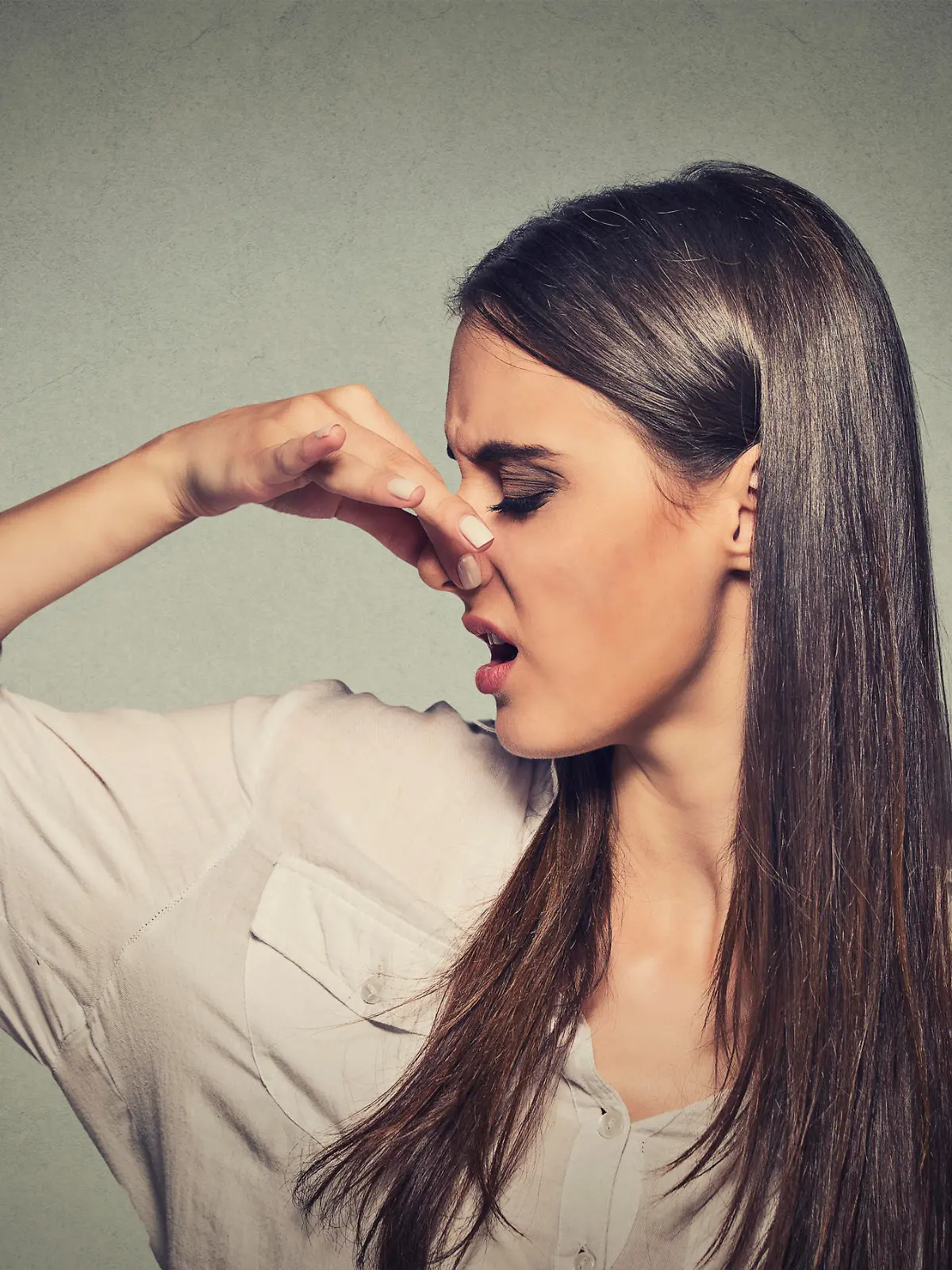 Side profile portrait headshot woman pinches nose with fingers looks with disgust away something stinks bad smell situation isolated gray wall background. Human face expression body language reaction.