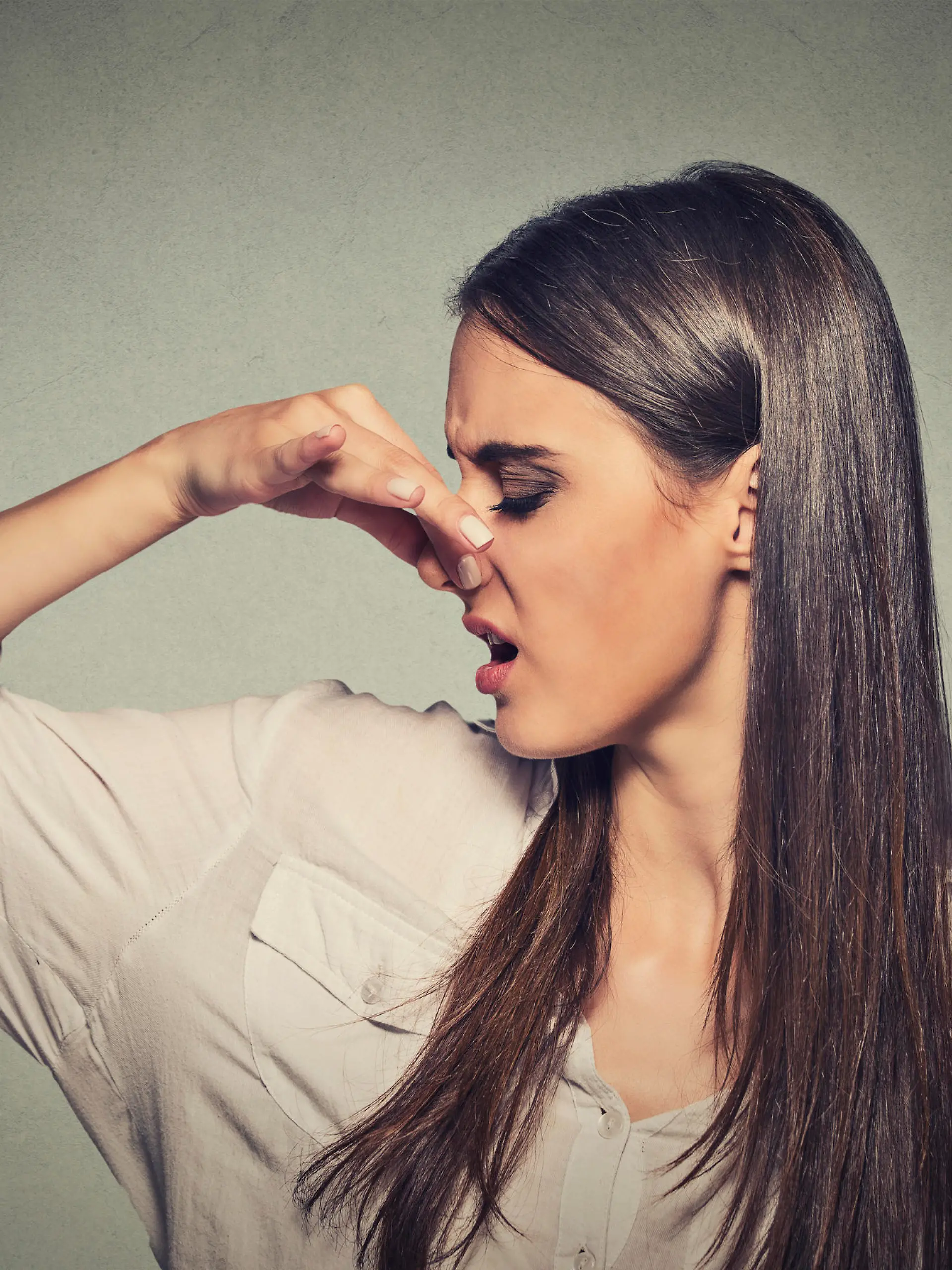 Side profile portrait headshot woman pinches nose with fingers looks with disgust away something stinks bad smell situation isolated gray wall background. Human face expression body language reaction.