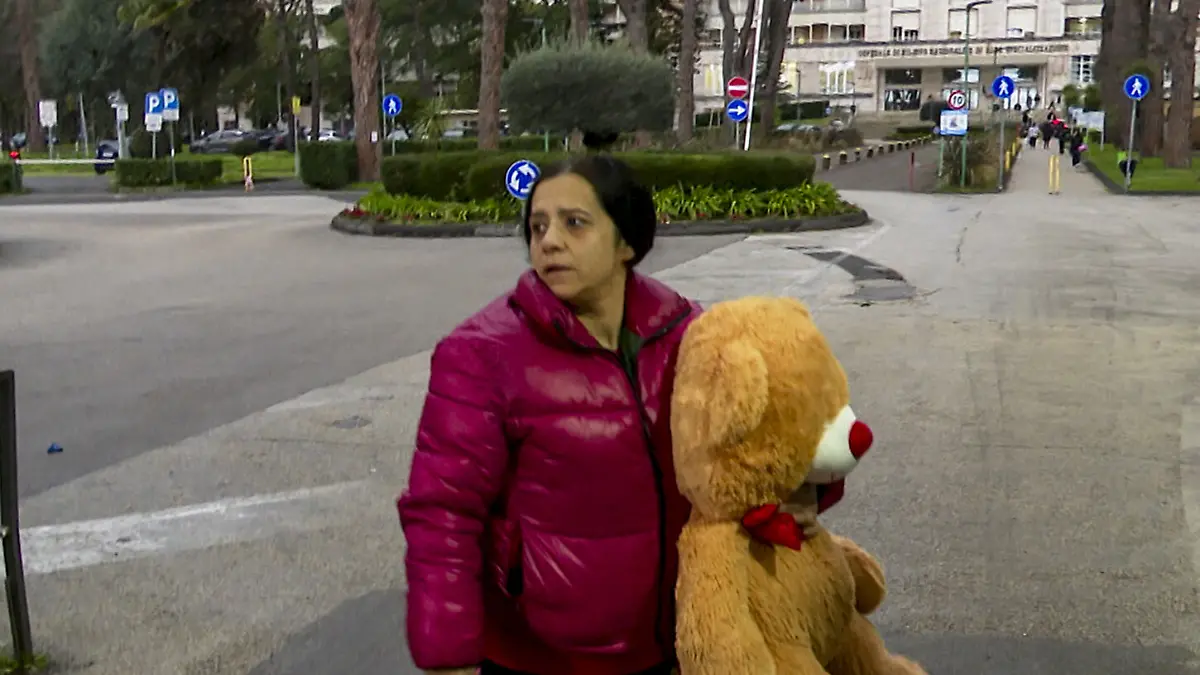 Die Mutter des kleinen Jungen läuft mit einem Kuscheltier zur Klinik. 