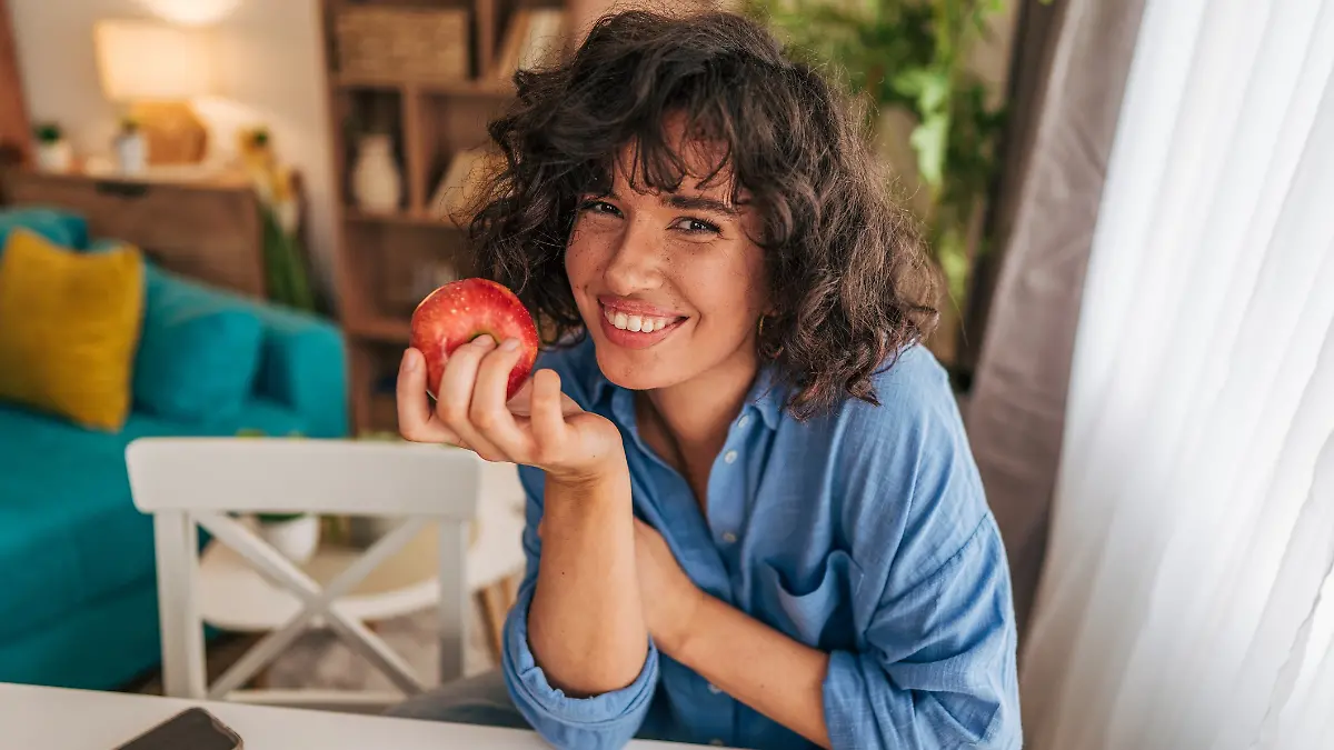 Frau isst einen Apfel und lächelt. 