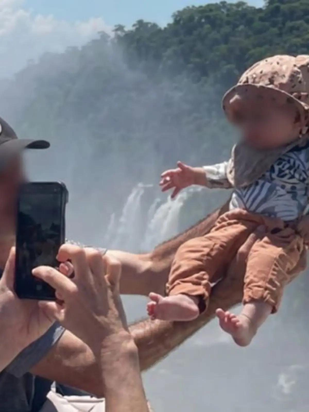 Vater hält Baby über den Abgrund