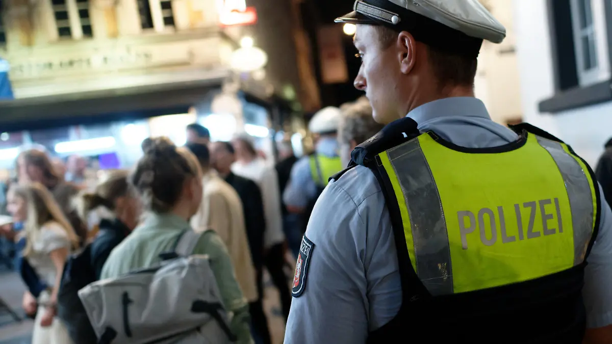 10.07.2021, Nordrhein-Westfalen, Düsseldorf: Polizisten im Dienst patrouillieren nach Mitternacht in der Altstadt zwischen Feiernden. Nach dem Wegfall der meisten Einschränkungen kehrt das Nachtleben in das Vergnügungsviertel zurück. Foto: Henning Kaiser/dpa +++ dpa-Bildfunk +++