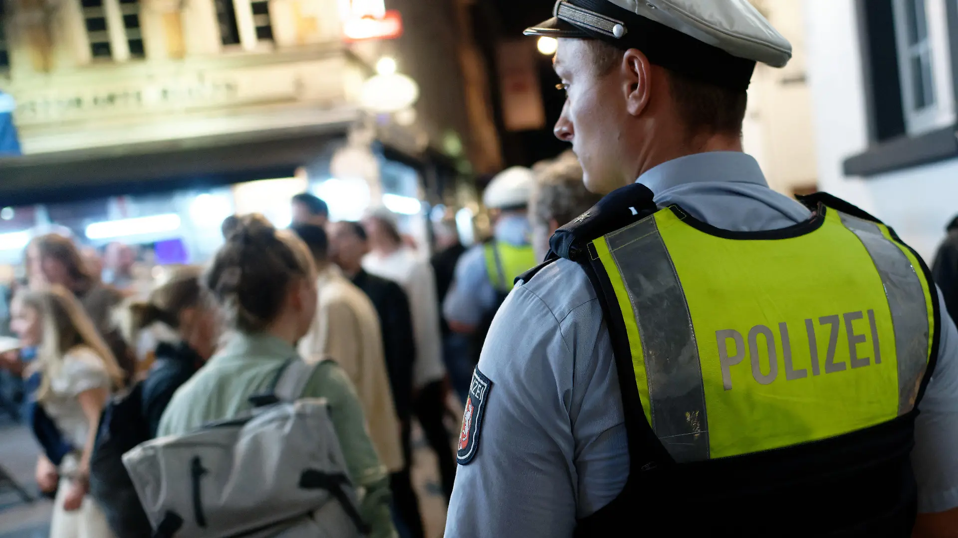 10.07.2021, Nordrhein-Westfalen, Düsseldorf: Polizisten im Dienst patrouillieren nach Mitternacht in der Altstadt zwischen Feiernden. Nach dem Wegfall der meisten Einschränkungen kehrt das Nachtleben in das Vergnügungsviertel zurück. Foto: Henning Kaiser/dpa +++ dpa-Bildfunk +++
