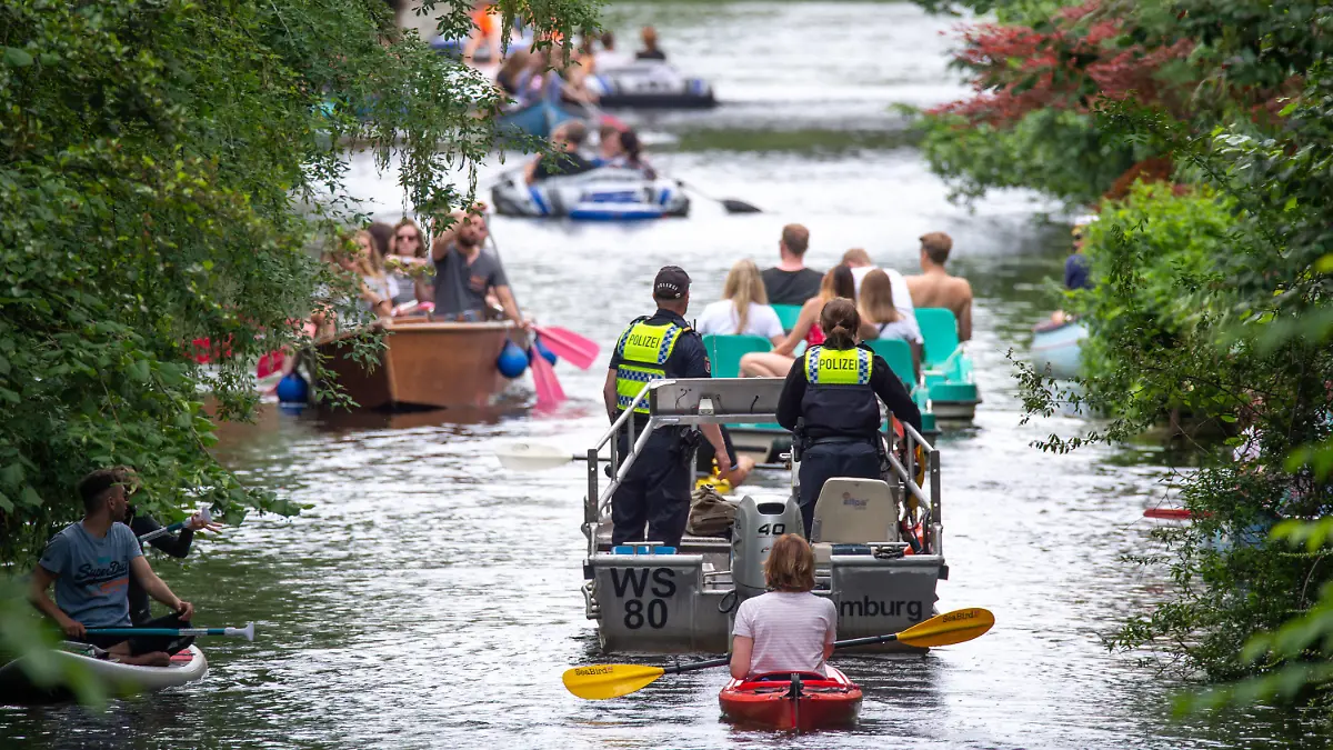 PRODUKTION - 10.07.2021, Hamburg: Wasserschutzpolizisten fahren mit einem Motorboot über den Mühlenkampkanal, auf dem viele mit Freizeitsportler unterwegs sind. An heißen Sommertagen wird es eng auf der Alster - vor allem in den Kanälen. Gefahren für Freizeitkapitäne und Natur sind die Folge. (zu dpa "Enge auf der Hamburger Alster - Suche nach Lösungen schwierig") Foto: Jonas Walzberg/dpa +++ dpa-Bildfunk +++