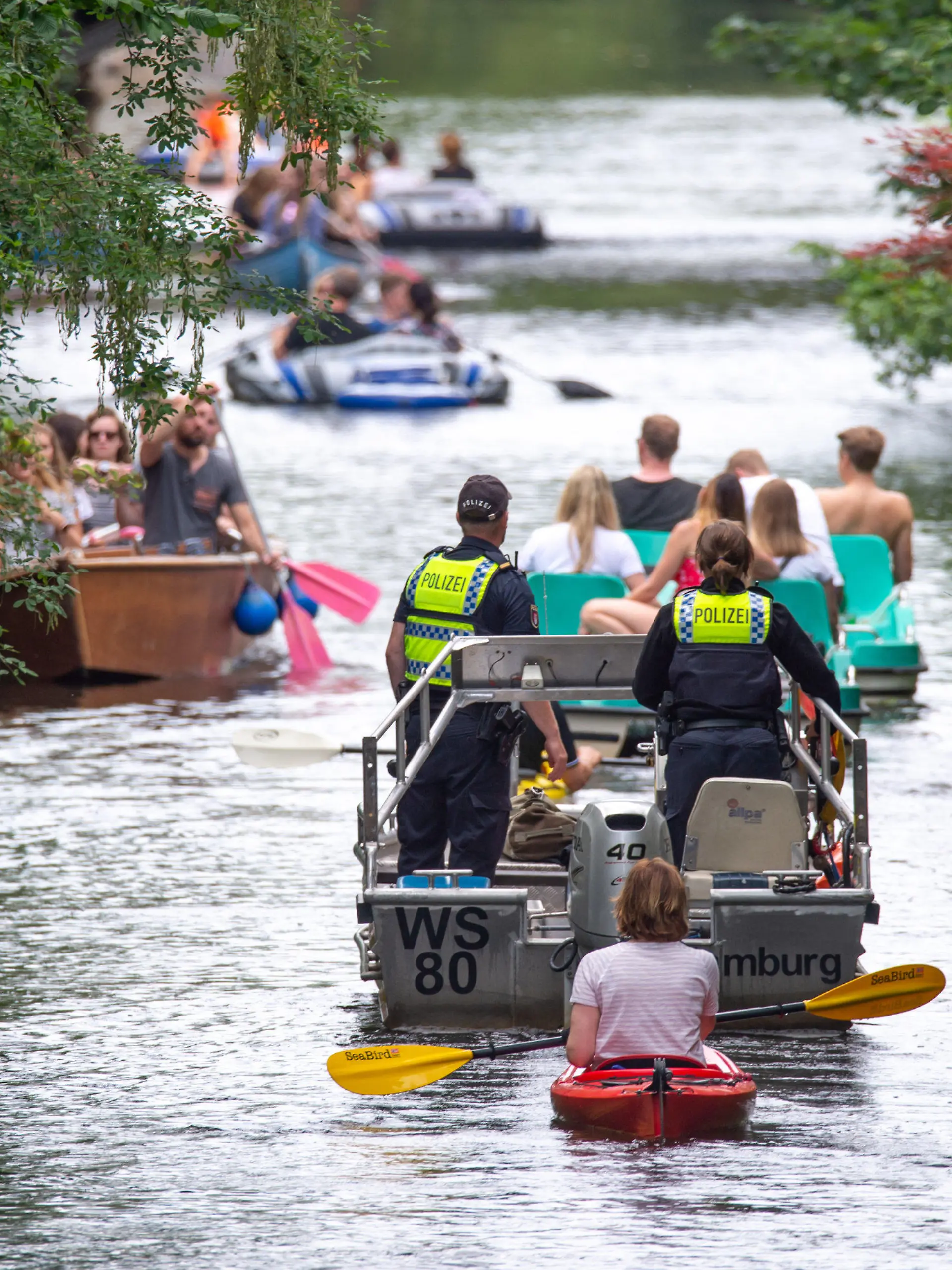PRODUKTION - 10.07.2021, Hamburg: Wasserschutzpolizisten fahren mit einem Motorboot über den Mühlenkampkanal, auf dem viele mit Freizeitsportler unterwegs sind. An heißen Sommertagen wird es eng auf der Alster - vor allem in den Kanälen. Gefahren für Freizeitkapitäne und Natur sind die Folge. (zu dpa "Enge auf der Hamburger Alster - Suche nach Lösungen schwierig") Foto: Jonas Walzberg/dpa +++ dpa-Bildfunk +++