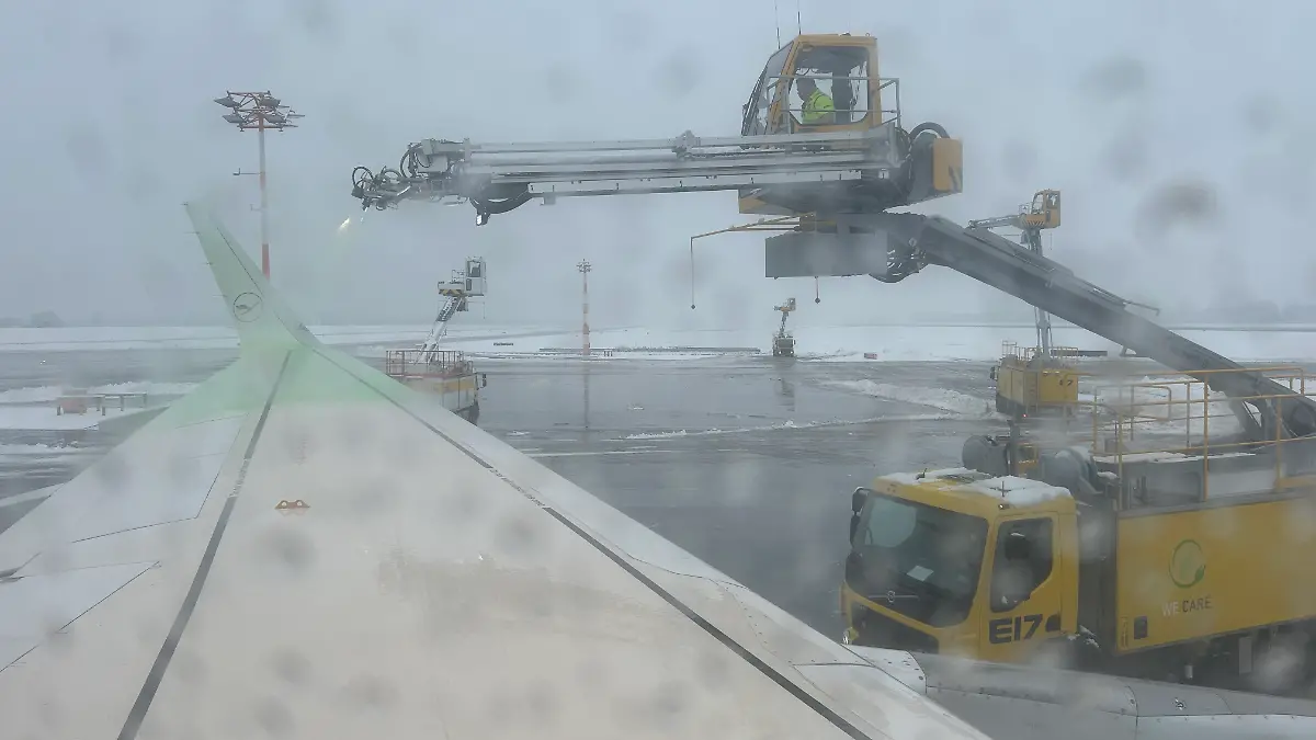 Ein Flugzeug von Lufthansa wird am Flughafen München enteist. Ein Fahrzeug spritzt Flüssigkeit auf die linke Tragfläche des Airbus.