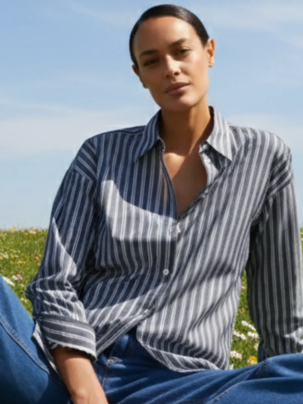 Frau trägt eine Bluse von Bonprix und sitzt auf einer Wiese.