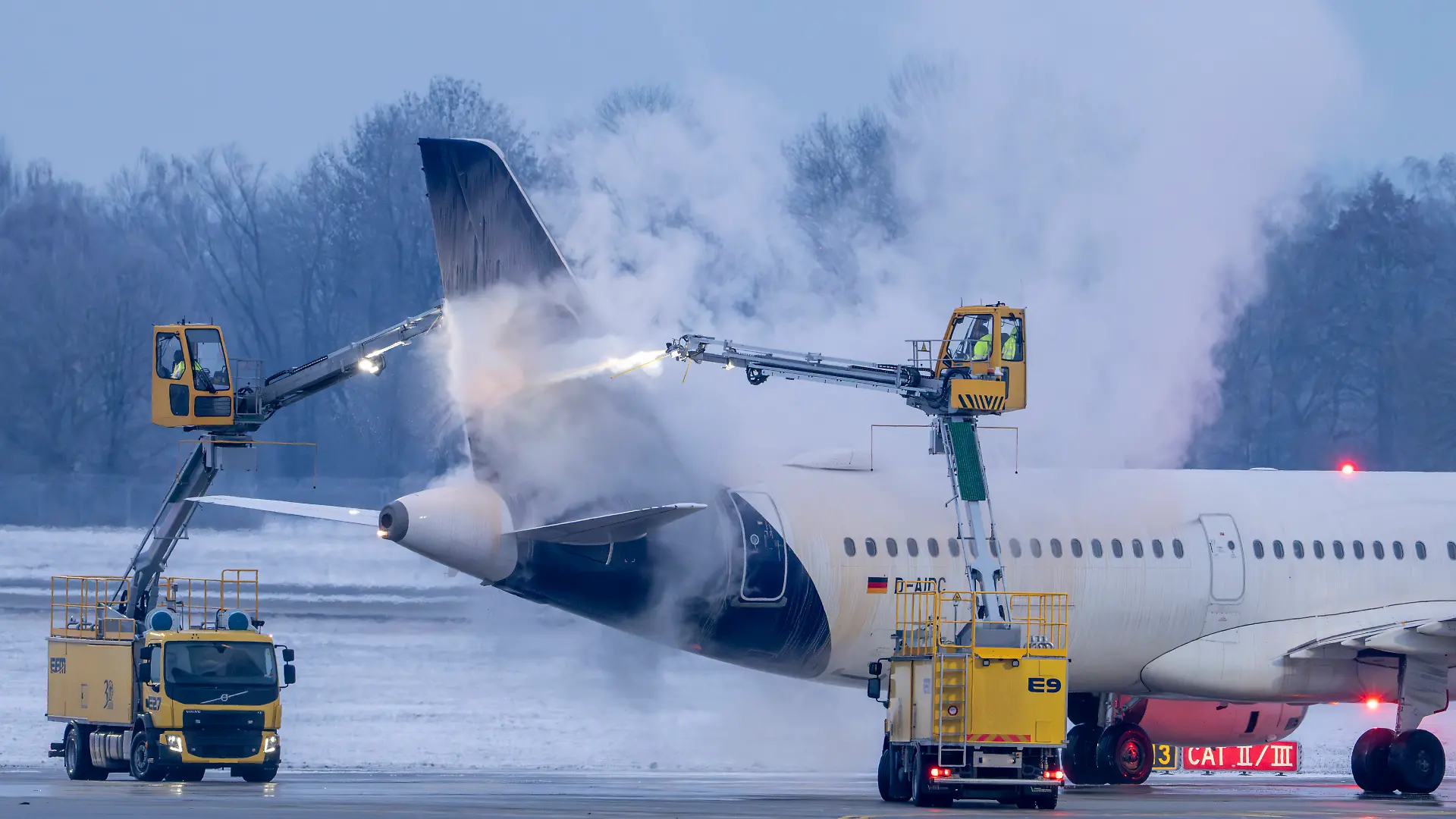 Am Flughafen München wird in den frühen Morgenstunden ein Flugzeug der Airline Lufthansa auf einer Enteisungsfläche von Spezialfahrzeugen enteist. +++ dpa-Bildfunk +++