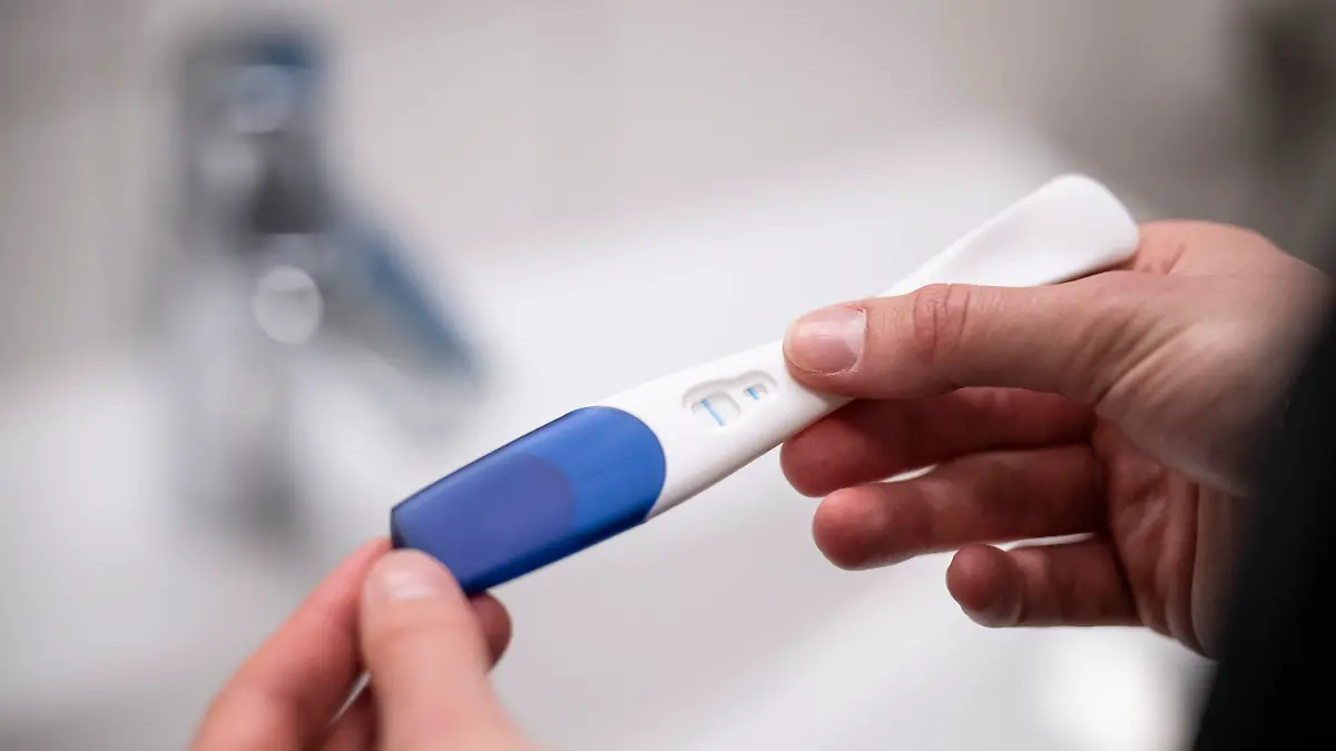 Ein Schwangerschaftstest wird in der Hand gehalten.