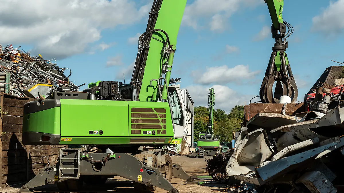 Grüner Bagger mit Greifer auf Schrottplatz, Deutschland