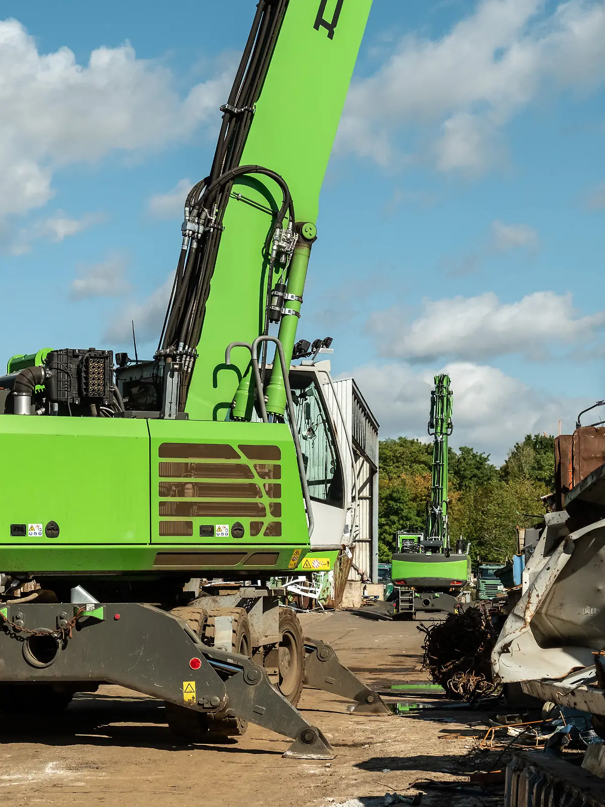 Grüner Bagger mit Greifer auf Schrottplatz, Deutschland