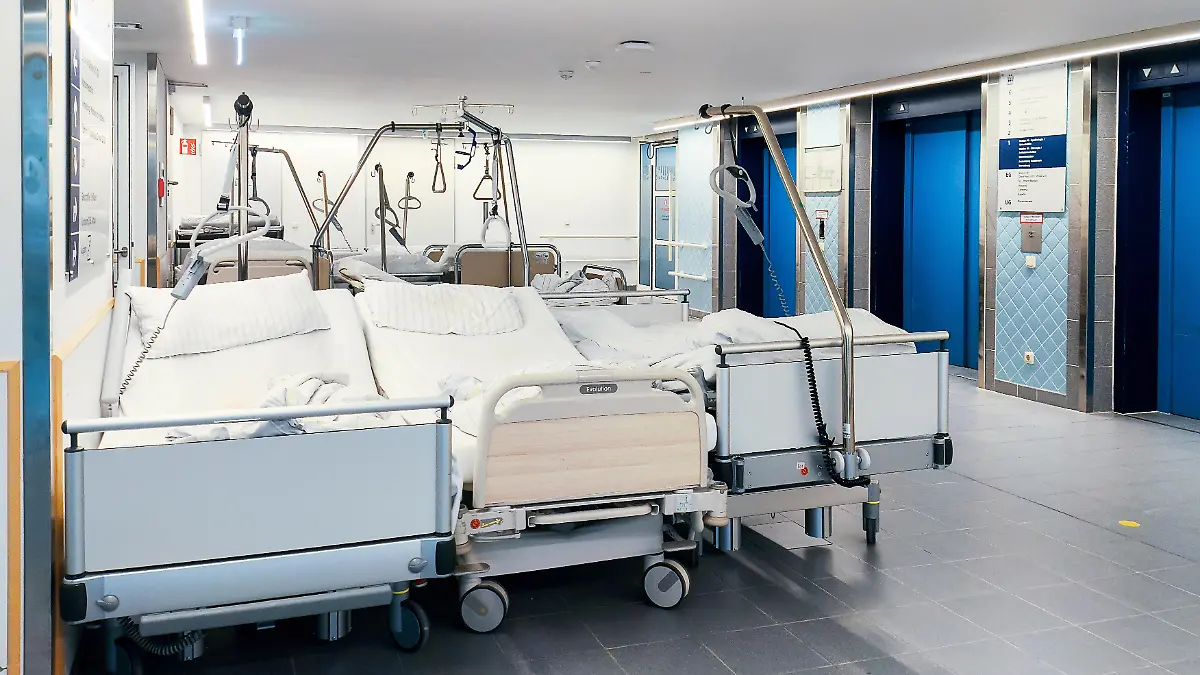 Mehrere gebrauchte Krankenhausbetten stehen unbesetzt auf einem Flur einer Klinik. Die Betten wurden bereits genutzt und sind aktuell nicht belegt. Der Klinikalltag mit leerstehenden Betten im Spannungsfeld von Entlassungen, Personalengpässen und strukturellen Herausforderungen im Gesundheitswesen
