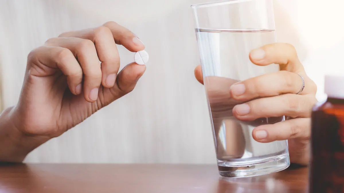 Woman s hand taking medicine pill and drinking water with the brown bottle on the table for healthcare concept. Copyright: x RECORD DATE NOT STATED