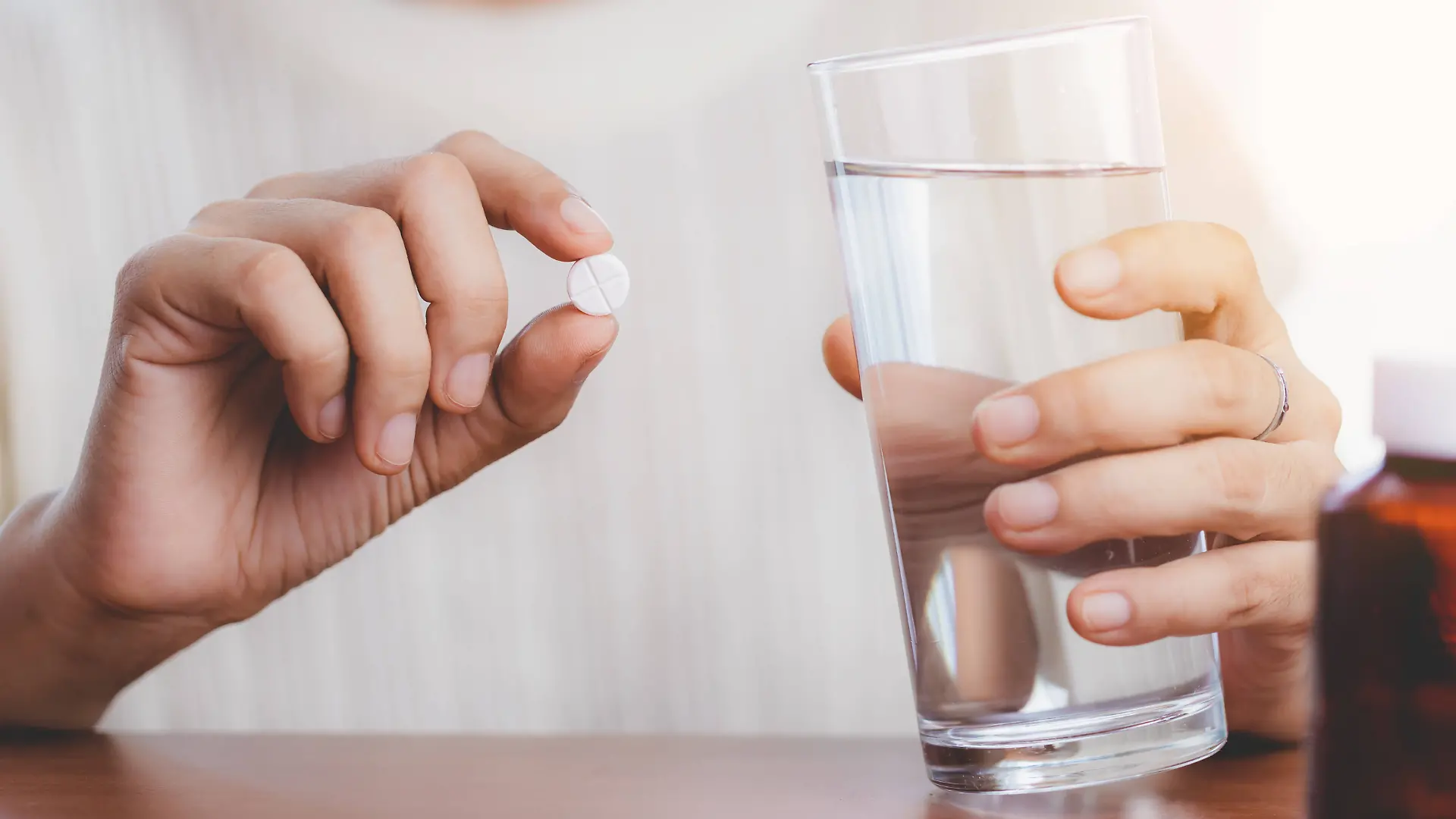 Woman s hand taking medicine pill and drinking water with the brown bottle on the table for healthcare concept. Copyright: x RECORD DATE NOT STATED