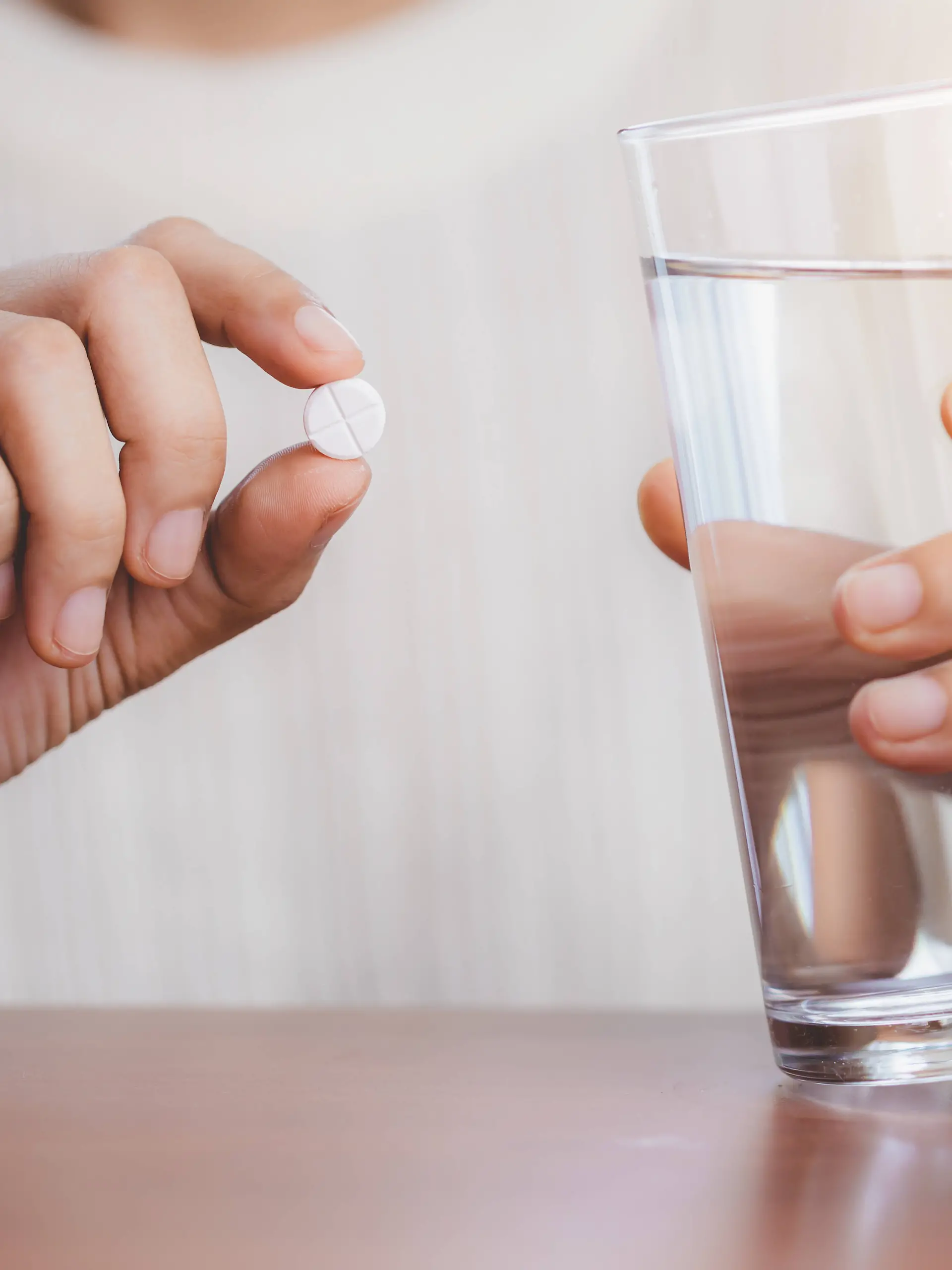 Woman s hand taking medicine pill and drinking water with the brown bottle on the table for healthcare concept. Copyright: x RECORD DATE NOT STATED