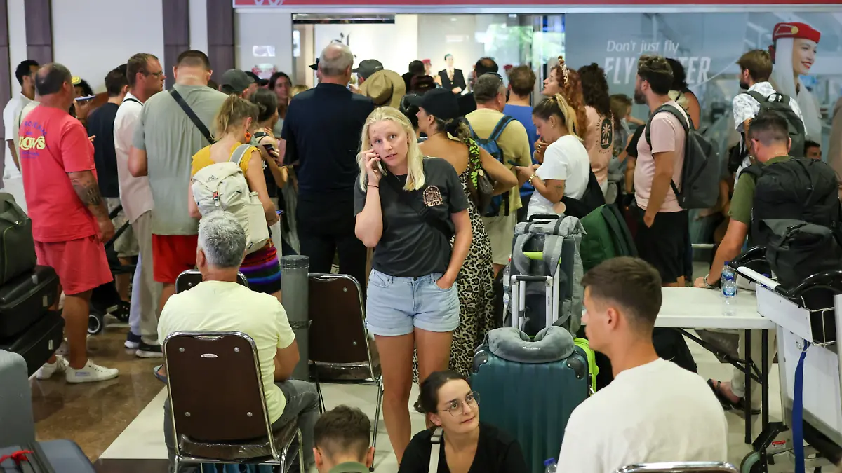 Stranded passengers wait near Emirates Airways customer service office at I Gusti Ngurah Rai International Airport after flights to Doha, Dubai, and Abu Dhabi were cancelled following strikes on Iran launched by the United States and Israel, in Kuta, Bali