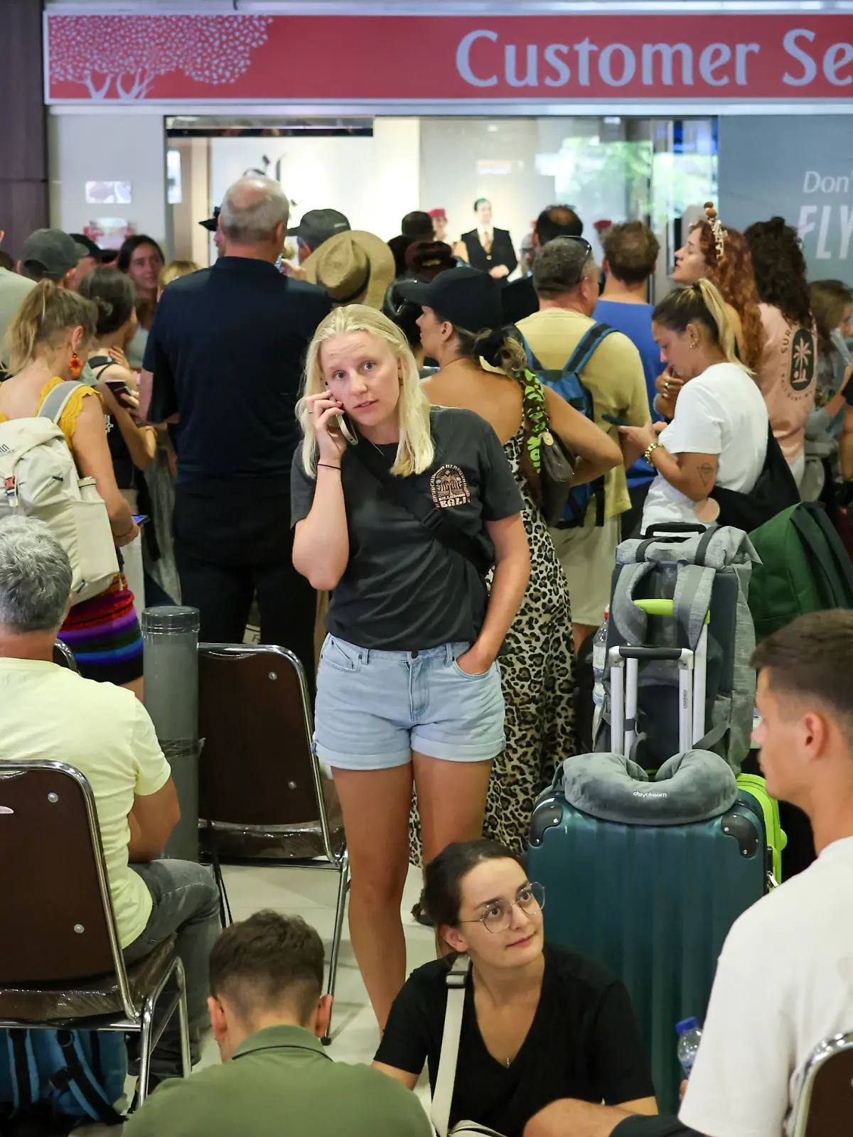 Stranded passengers wait near Emirates Airways customer service office at I Gusti Ngurah Rai International Airport after flights to Doha, Dubai, and Abu Dhabi were cancelled following strikes on Iran launched by the United States and Israel, in Kuta, Bali