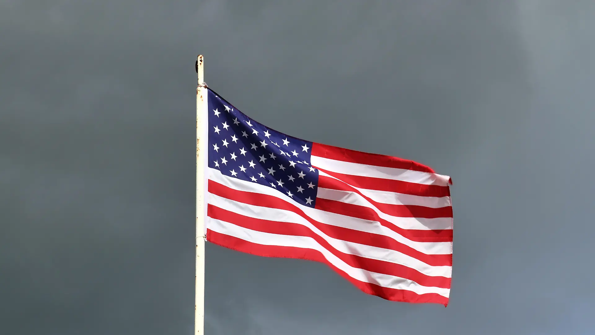USA-Flagge an einem Fahnenmast, die sich im Wind gegen den Himmel bewegt