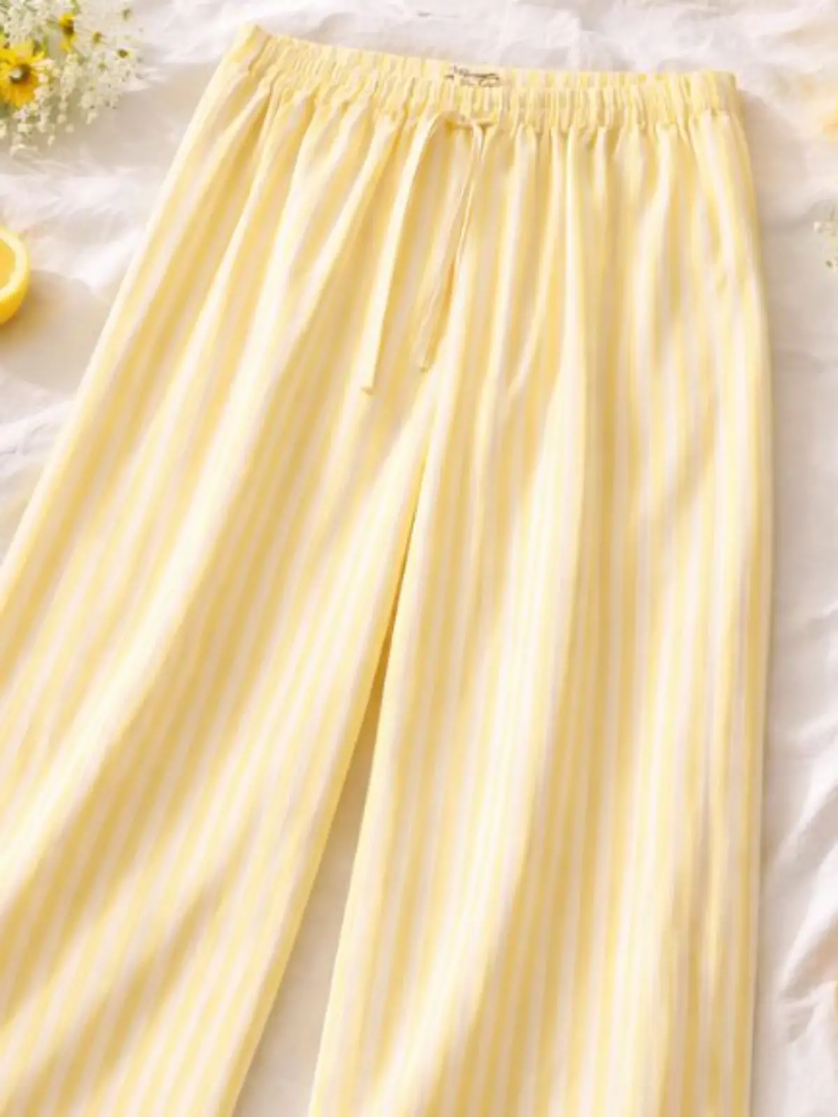 Die hellgelb-weiße Marlenehose aus Viskose-Mix kombiniert luftige Weite mit frischer Frühlingsfarbe.