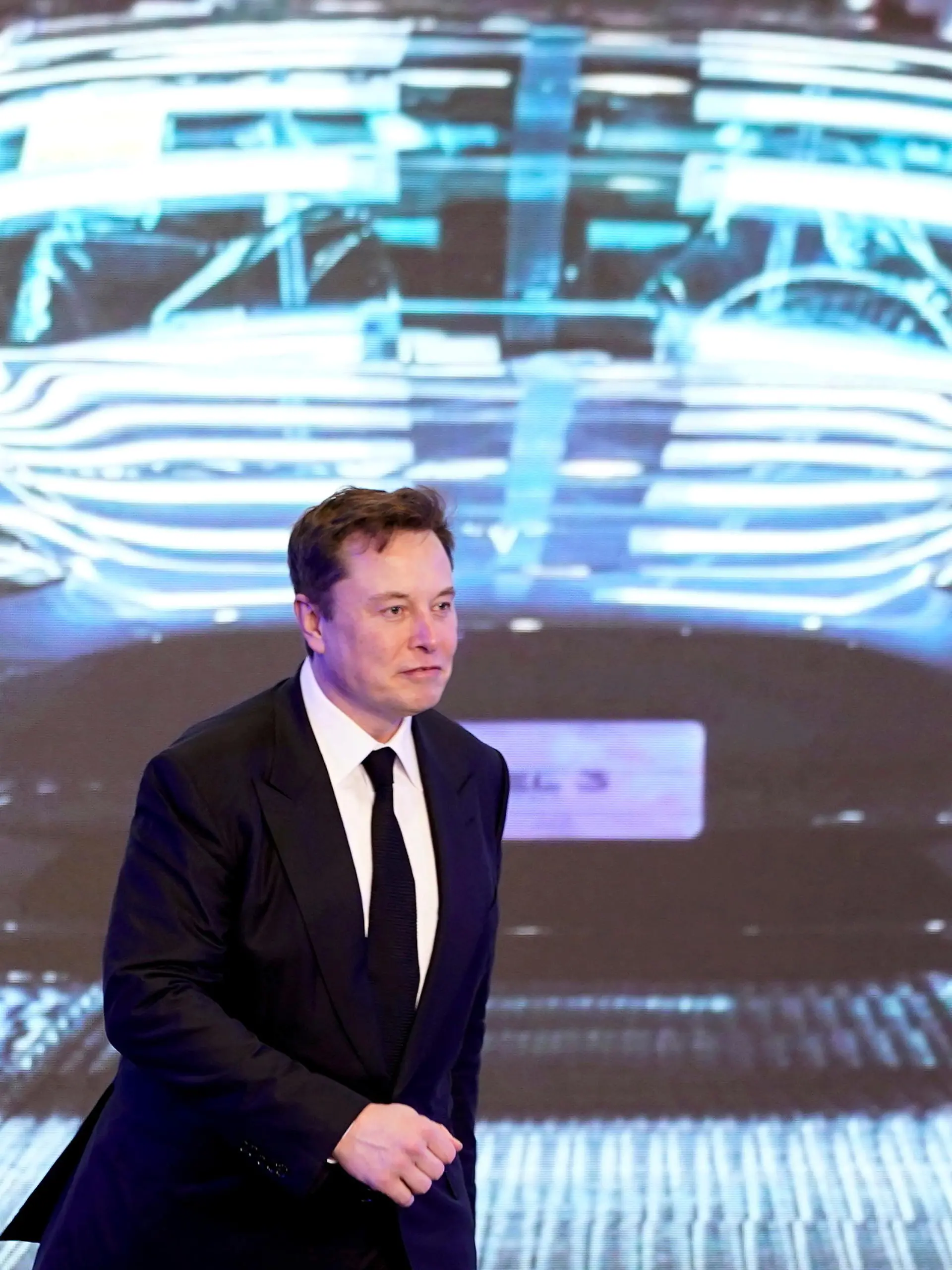 FILE PHOTO: Tesla Inc CEO Elon Musk walks next to a screen showing an image of Tesla Model 3 car during an opening ceremony for Tesla China-made Model Y program in Shanghai, China January 7, 2020. REUTERS/Aly Song/File Photo