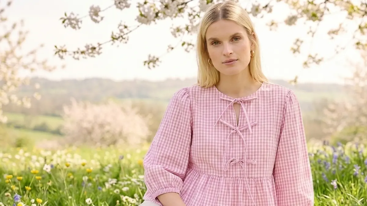 Frau sitzt auf einer Picknick-Decke und trägt eine Bluse von Bonprix.