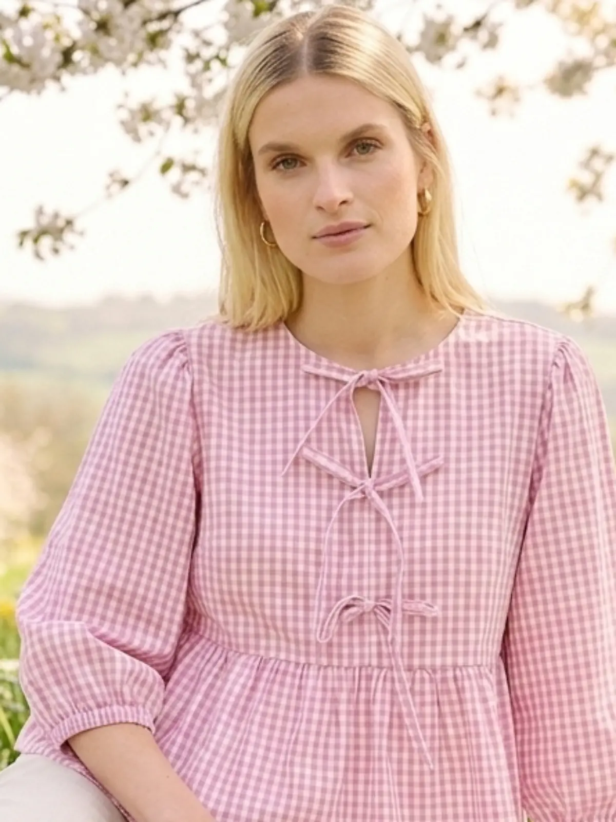 Frau sitzt auf einer Picknick-Decke und trägt eine Bluse von Bonprix.