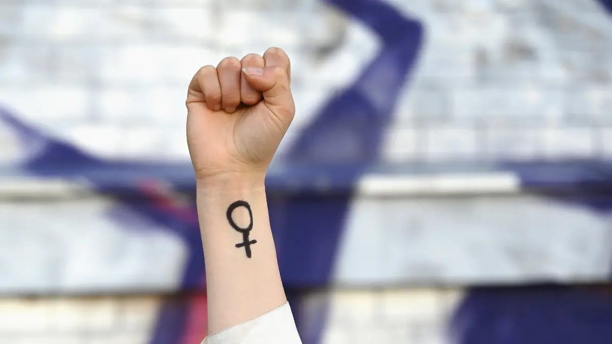 ILLUSTRATION - 07.03.2025, Sachsen, Leipzig: Eine Frau hebt ihre Faust in die Höhe. Auf ihrem Arm ist das Venussymbol zu sehen, das für das weibliche Geschlecht und Frauenrechte steht.  (zu dpa: «Generationen-Umfrage: Gen-Z hat rückständigstes Rollendenken») Foto: Elisa Schu/dpa +++ dpa-Bildfunk +++