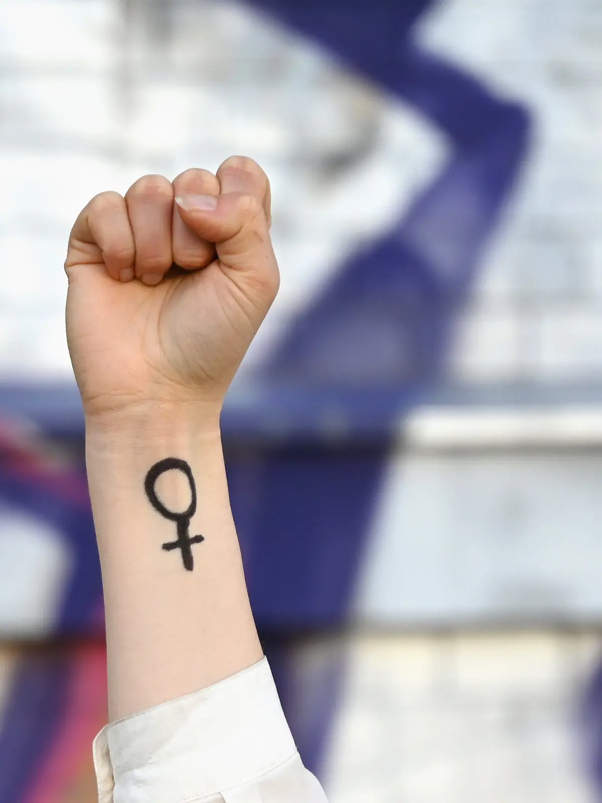 ILLUSTRATION - 07.03.2025, Sachsen, Leipzig: Eine Frau hebt ihre Faust in die Höhe. Auf ihrem Arm ist das Venussymbol zu sehen, das für das weibliche Geschlecht und Frauenrechte steht.  (zu dpa: «Generationen-Umfrage: Gen-Z hat rückständigstes Rollendenken») Foto: Elisa Schu/dpa +++ dpa-Bildfunk +++