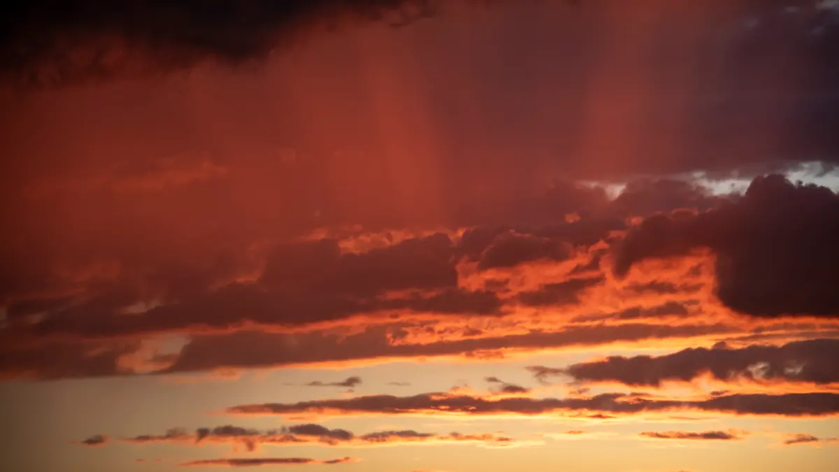 Die untergehende Sonne hat den Wolkenhimmel rot verfärbt.