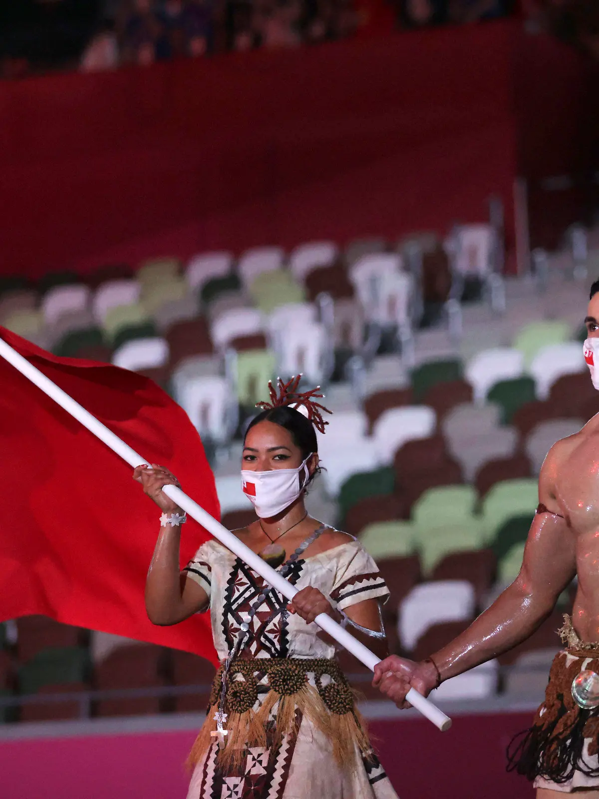 Malia Paseka and Pita Taufatofua, of Tonga, carry their country's flag during the opening ceremony in the Olympic Stadium at the 2020 Summer Olympics, Friday, July 23, 2021, in Tokyo, Japan. (Hannah McKay/Pool Photo via AP)