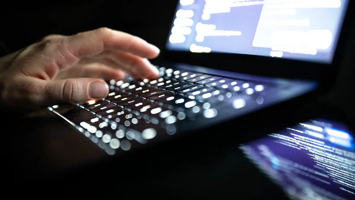 ILLUSTRATION - 14.12.2025, NA, Berlin: Eine Person tippt mit den Fingern auf einer beleuchteten Laptop-Tastatur.(gestellte Szene) (zu dpa: «Studie: Hacker legen Betrieb bei vielen Unternehmen lahm») Foto: Philip Dulian/dpa +++ dpa-Bildfunk +++