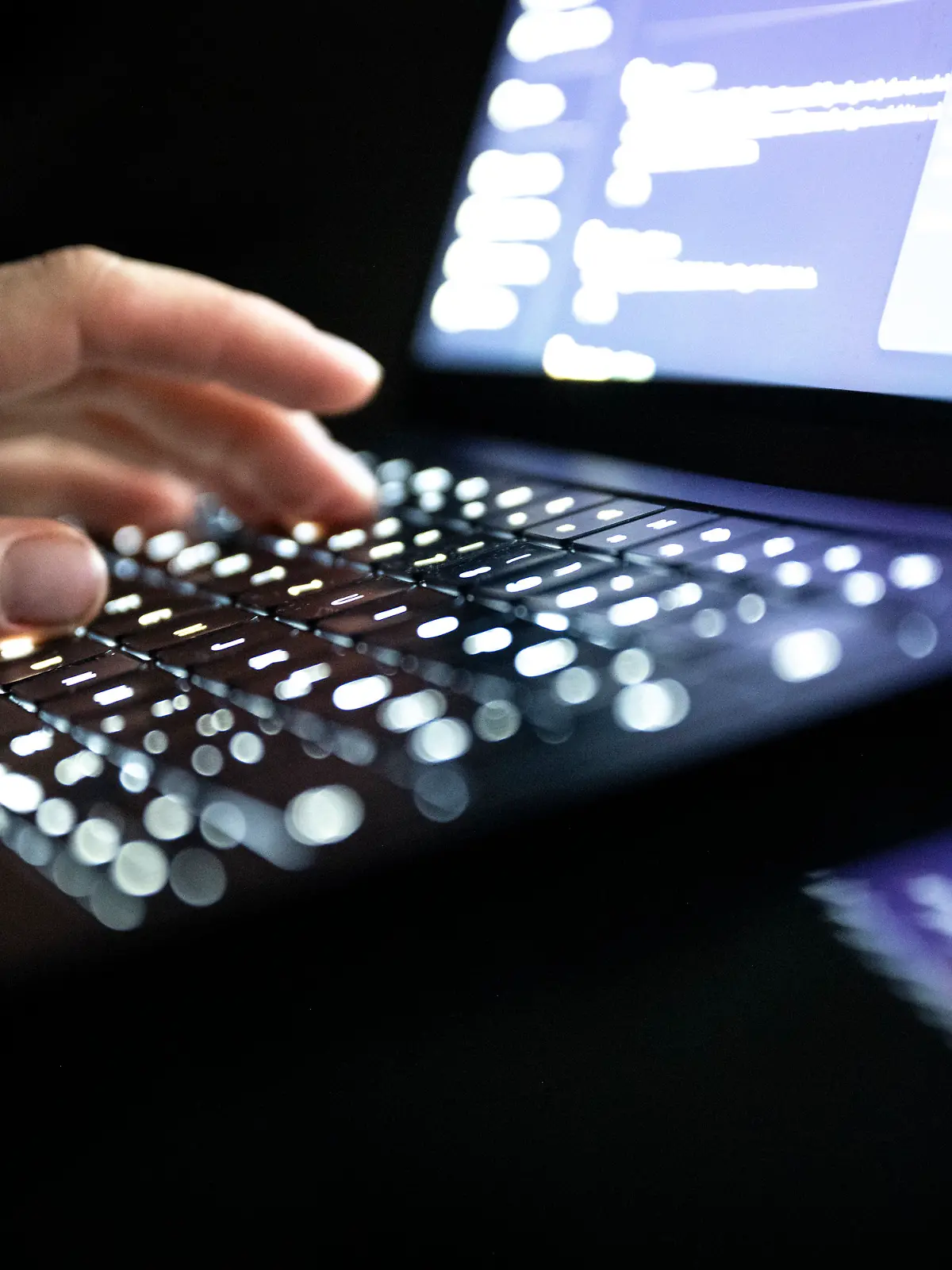 ILLUSTRATION - 14.12.2025, NA, Berlin: Eine Person tippt mit den Fingern auf einer beleuchteten Laptop-Tastatur.(gestellte Szene) (zu dpa: «Studie: Hacker legen Betrieb bei vielen Unternehmen lahm») Foto: Philip Dulian/dpa +++ dpa-Bildfunk +++