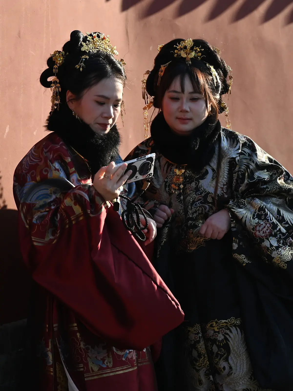 PRODUKTION - 17.02.2026, China, Peking: Zwei Frauen fotografieren sich an der roten Mauer des bei Peking-Touristen beliebten Trommelturms. Auf sozialen Medien macht ein Trend die Runde, sich besonders chinesisch zu verhalten und Gebräuche nachzuahmen. (zu dpa: «Warme Füße und Reisbrei: Warum China plötzlich Trend ist») Foto: Johannes Neudecker/dpa +++ dpa-Bildfunk +++