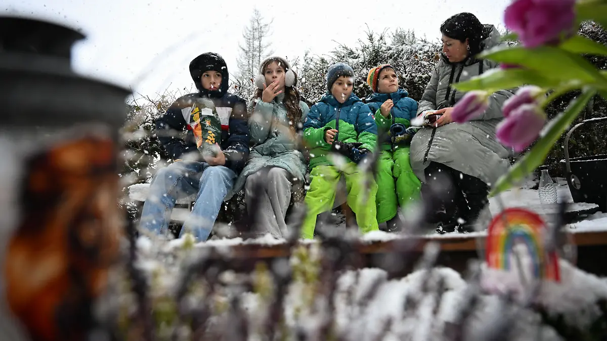 Ben (v-l), Ida, Tom und Theo picknicken gemeinsam mit ihrer Mutter Christina Schmid auf einer Bank am Gab ihres Vaters. Der Familienvater starb 2023 an Krebs. Auf seinem Grab steht ein Grabstein mit Briefschlitz, in den die Familie Briefe einwerfen kann. +++ dpa-Bildfunk +++