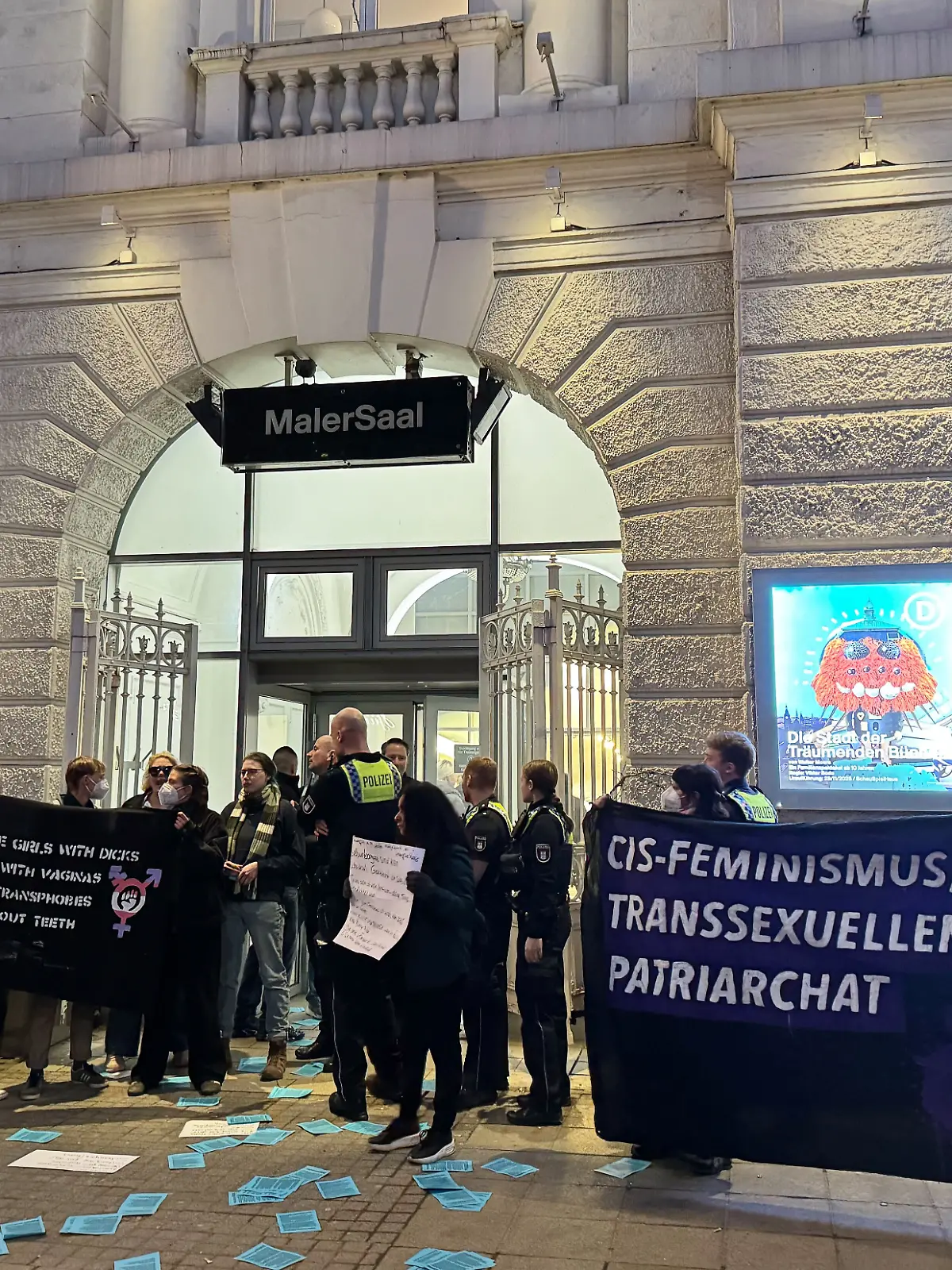 Mehrere Menschen protestieren am Weltfrauentag vor dem Malersaal des Schauspielhauses gegen den Auftritt von Feministin Alice Schwarzer.