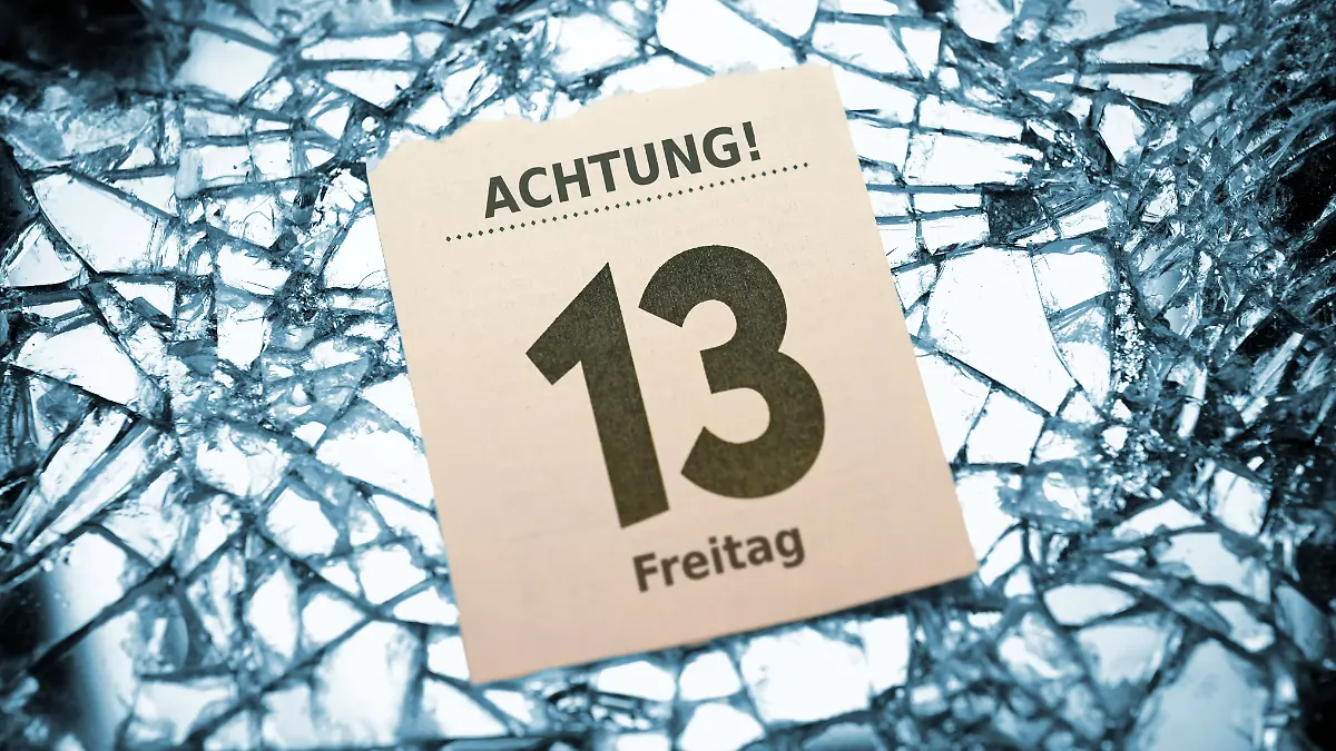 Kalenderblatt, das Freitag, den 13. zeigt, gebettet auf einem Scherbenhaufen eines zerbrochenen Spiegels